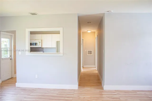a view of a hallway with wooden floor and a bathroom