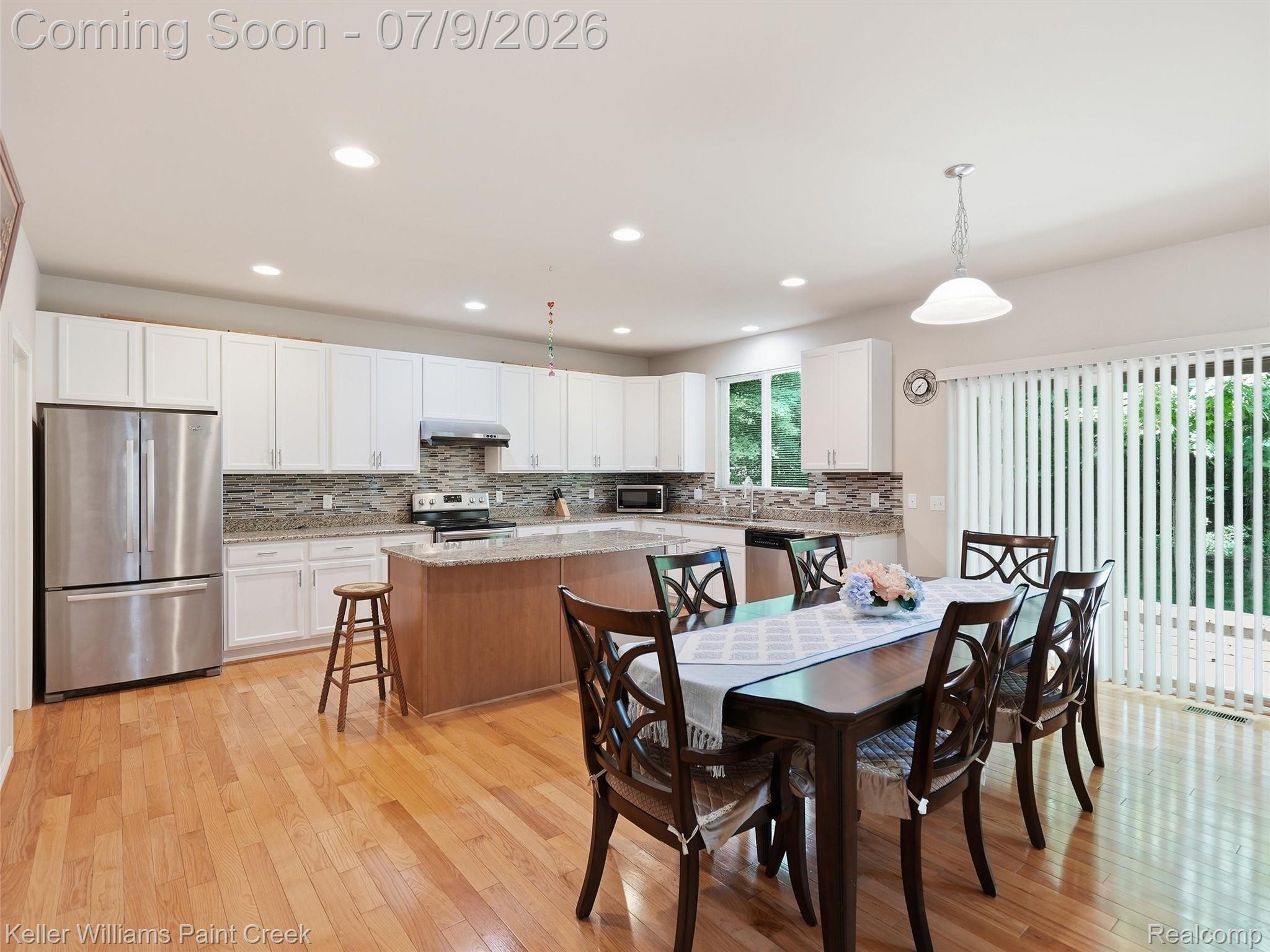 846 Monterey Ln. Rochester, MI 48307 - Photo 13 of 52 Open-concept kitchen and dining area featuring hardwood flooring, white cabinetry, stainless steel appliances, and a central island with a granite countertop