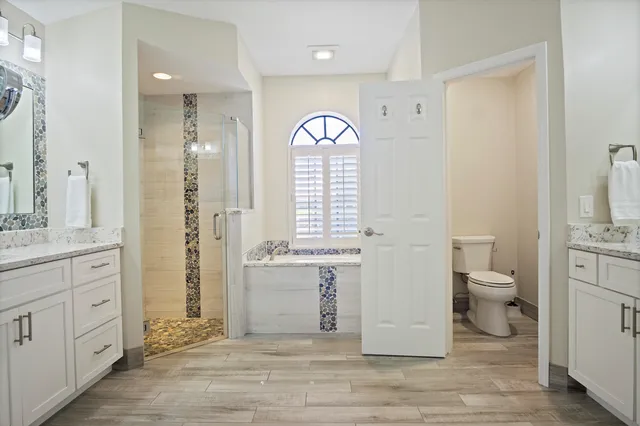 a spacious bathroom with a granite countertop toilet a sink a mirror and a window