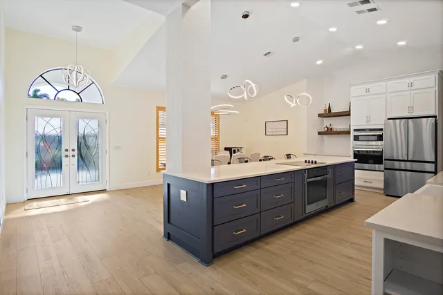 a kitchen with stainless steel appliances kitchen island granite countertop a stove a refrigerator a sink and a dining table with wooden floor