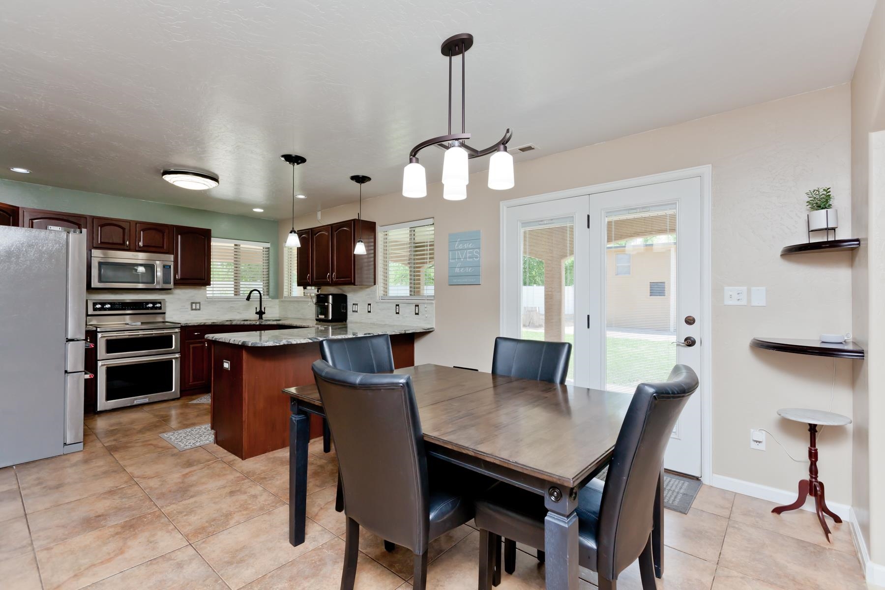718 Sabil Drive Fruita, CO 81521 - Photo 5 of 35 a kitchen with stainless steel appliances kitchen island granite countertop a table chairs and a refrigerator
