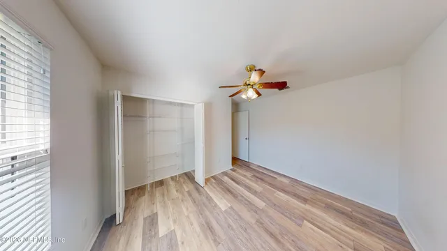 a view of a room with wooden floor and ceiling fan