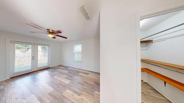 a view of an empty room with wooden floor and a window