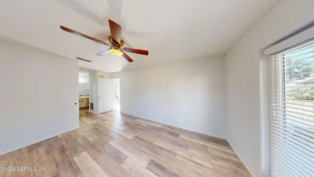 a view of empty room with wooden floor and fan