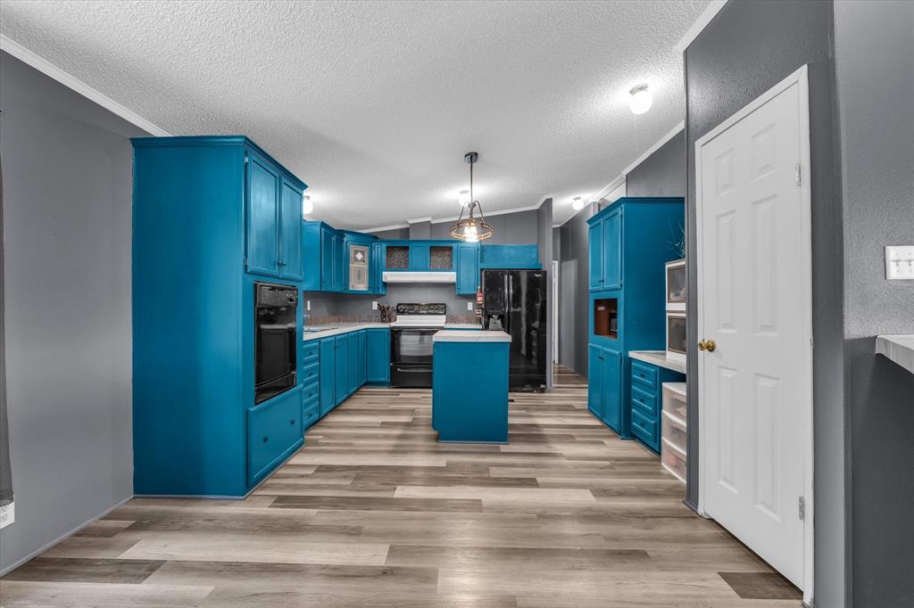 3615 Spring Valley Road Lorena, TX 76655 - Photo 6 of 33 Spacious kitchen featuring extensive blue cabinetry, a central island, integrated black appliances, and wood-finish flooring