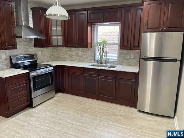 a kitchen with stainless steel appliances granite countertop a refrigerator a sink dishwasher a stove with wooden cabinets and floors