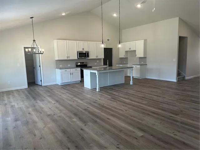 a kitchen with stainless steel appliances kitchen island granite countertop a refrigerator a oven and a wooden floors