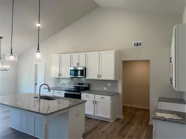 a kitchen with kitchen island granite countertop a sink stainless steel appliances and white cabinets