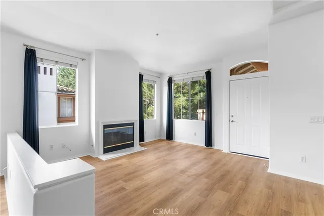 a view of an empty room with window and kitchen view