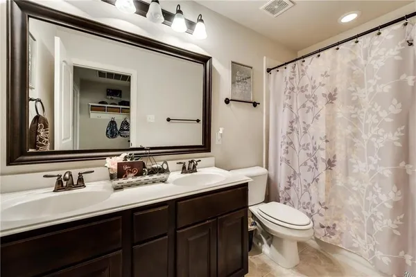 a bathroom with a double vanity sink toilet mirror and shower