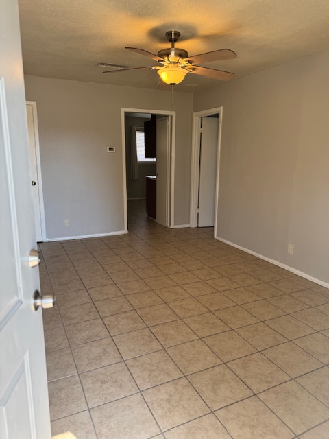 1802 West Avenue H, Unit A Temple, TX 76504 - Photo 2 of 6 Unfurnished room with a ceiling fan, a textured ceiling, and light tile patterned floors