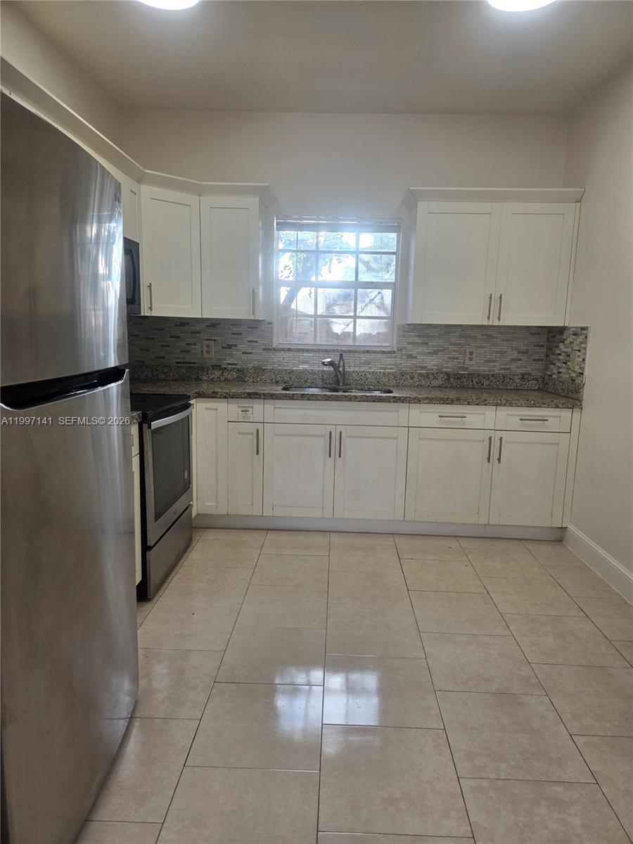 9740 Northwest 5th Avenue Miami, FL 33150 - Photo 6 of 18 a kitchen with kitchen island granite countertop a stove a sink and a refrigerator