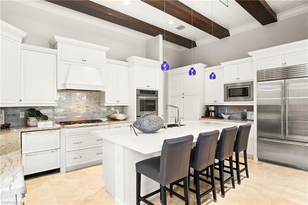 2220 Residence Circle Naples, FL 34105 - Photo 8 of 50 a kitchen with stainless steel appliances granite countertop a stove a refrigerator a kitchen island with white cabinets and wooden floor