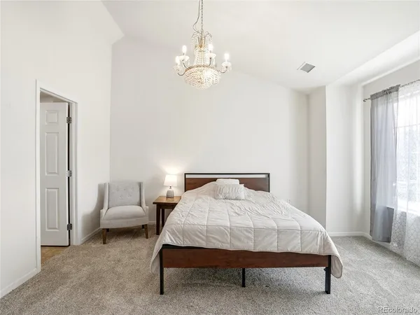 a spacious bedroom with a bed and a chandelier