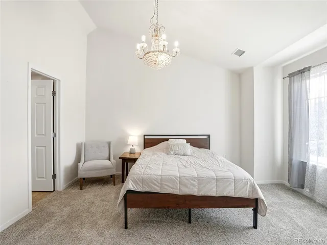 a spacious bedroom with a bed and a chandelier