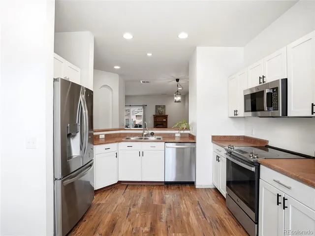 a kitchen with stainless steel appliances granite countertop a stove top oven a sink and a refrigerator