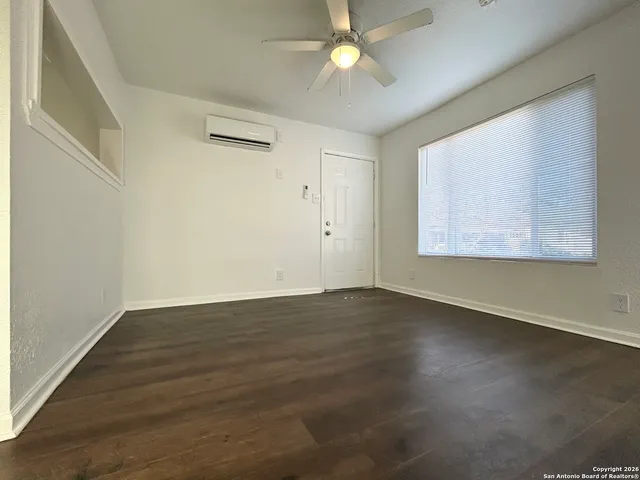 an empty room with wooden floor fan and windows
