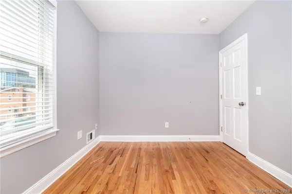 an empty room with wooden floor and windows