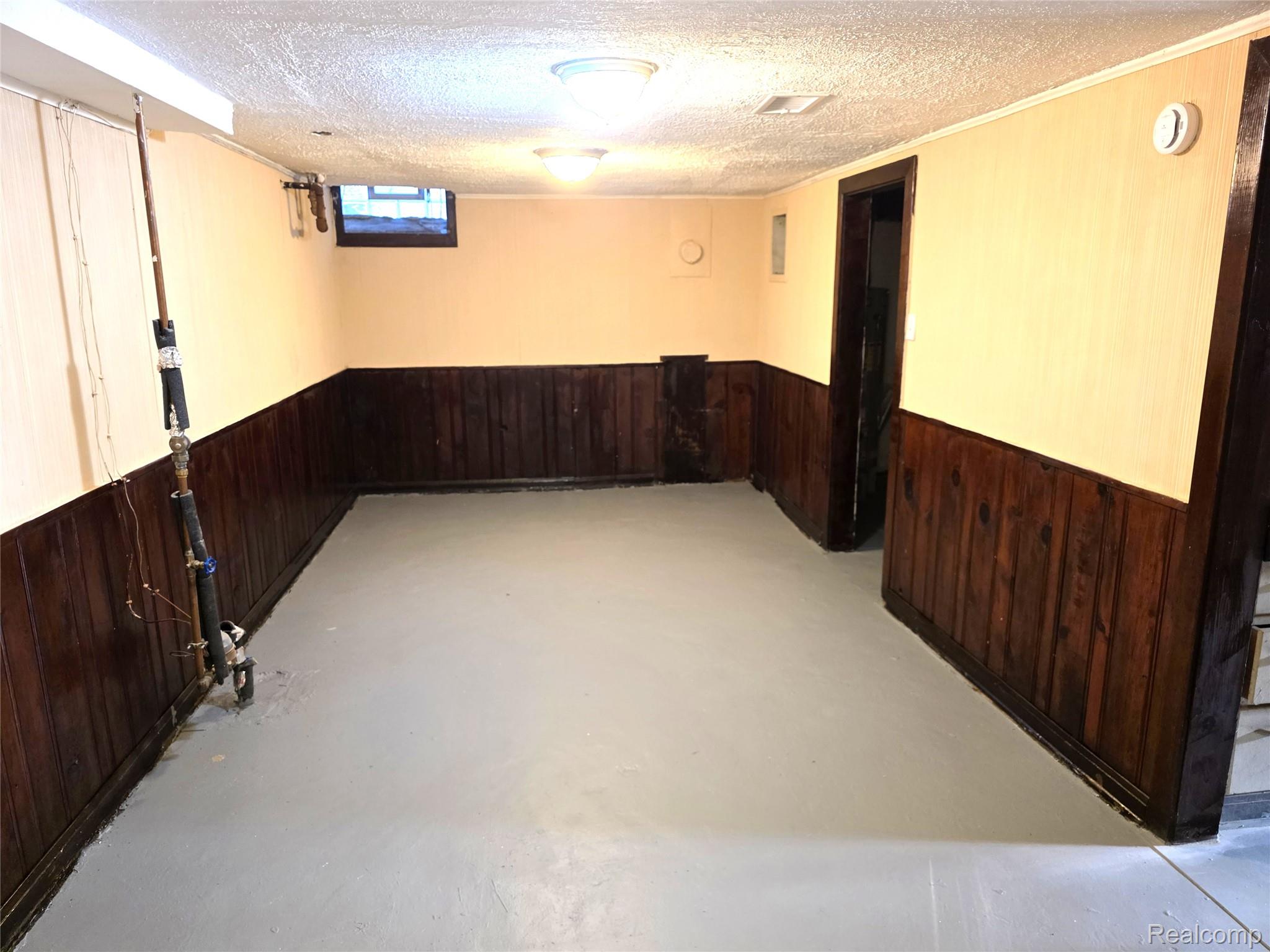 16814 Strathmoor Street Detroit, MI 48235 - Photo 21 of 31 Finished lower-level space with painted flooring, wood paneling, and an exposed ceiling beam