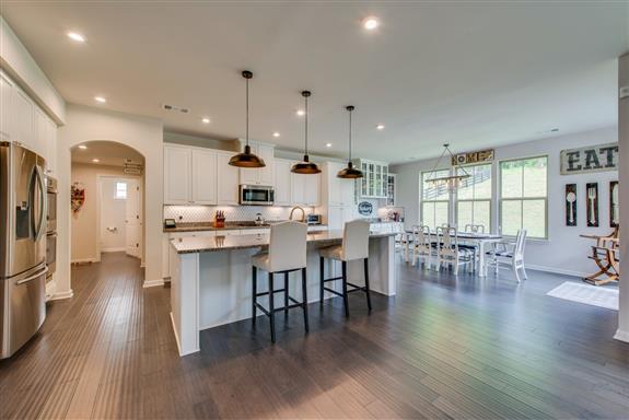 an open kitchen with wooden floor and stainless steel appliances