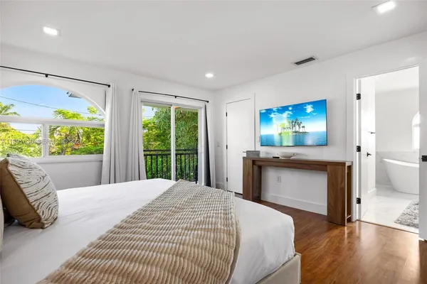 a bedroom with a large bed and a wooden floor