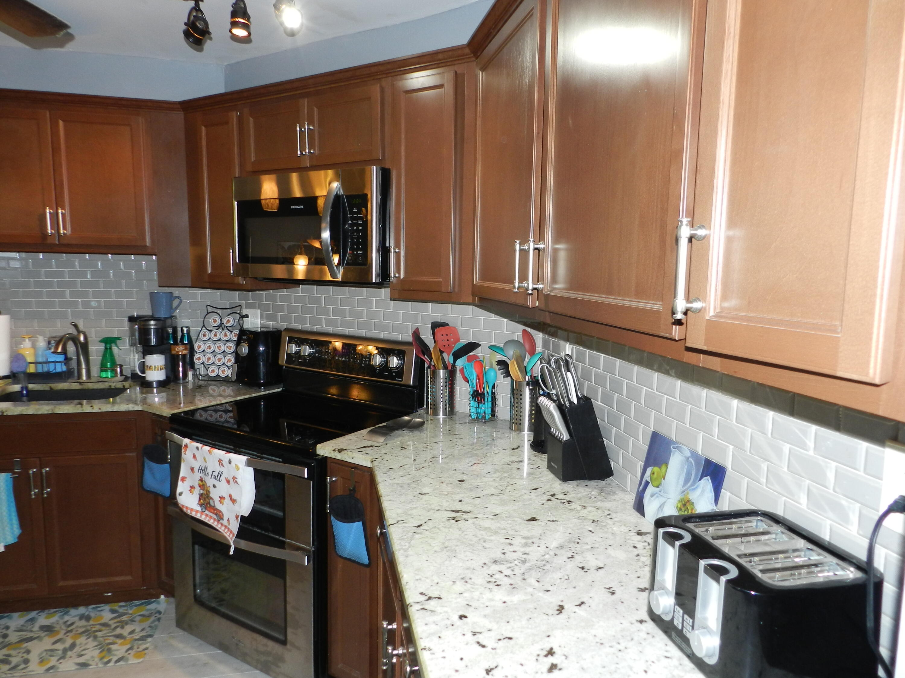 7 Greenway Village North, Unit 103 Royal Palm Beach, FL 33411 - Photo 3 of 29 a kitchen with a stove a sink and a microwave