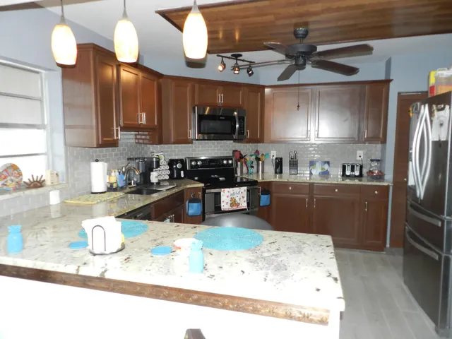 a kitchen with stainless steel appliances granite countertop a sink a stove and a refrigerator