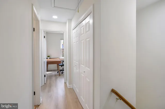 a view of a hallway with wooden floor and a bathroom