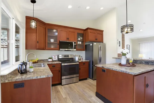 a kitchen with stainless steel appliances granite countertop a sink a stove a refrigerator a center island with wooden floor