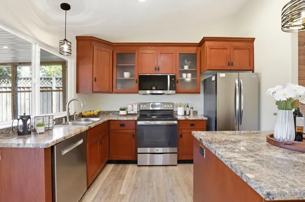 a kitchen with stainless steel appliances granite countertop a stove a sink dishwasher a refrigerator and a microwave oven with wooden floor