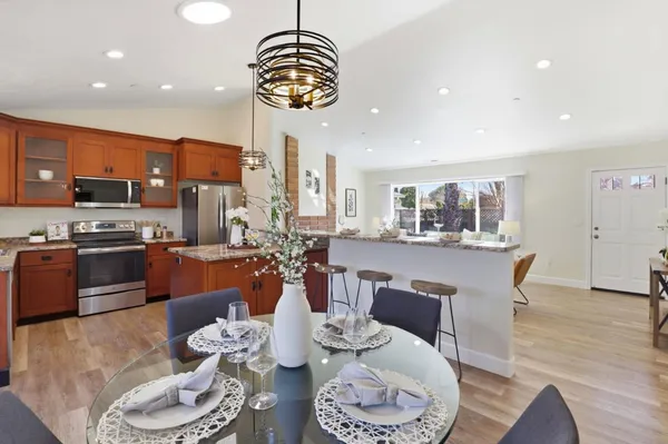 a dining room with stainless steel appliances kitchen island granite countertop a table and chairs