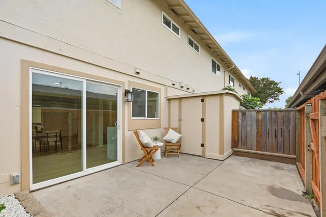 a view of a patio with table and chairs and floor to ceiling window and potted plants