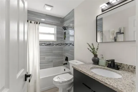 a bathroom with a granite countertop sink toilet mirror and shower