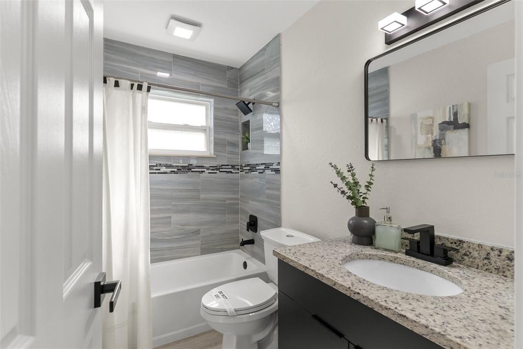 12368 70th Street Largo, FL 33773 - Photo 26 of 33 a bathroom with a granite countertop sink toilet mirror and shower