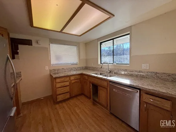a kitchen with granite countertop a sink cabinets stainless steel appliances and a window