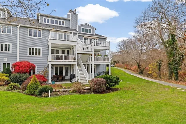 a view of a house with a big yard potted plants and a large tree