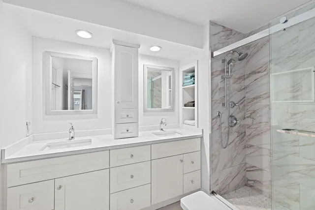 a bathroom with a double vanity sink mirror and shower