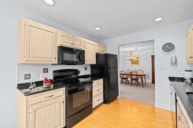 a kitchen with stainless steel appliances granite countertop a stove top oven a sink dishwasher a dining table and chairs with wooden floor