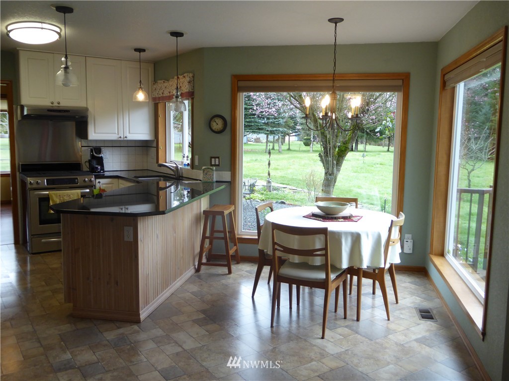 9527 Gastaeson Lane Southwest Rochester, WA 98579 - Photo 11 of 40 a kitchen with kitchen island granite countertop a stove a sink a dining table and chairs with wooden floor