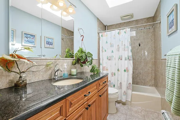 a bathroom with a granite countertop sink a toilet and a mirror