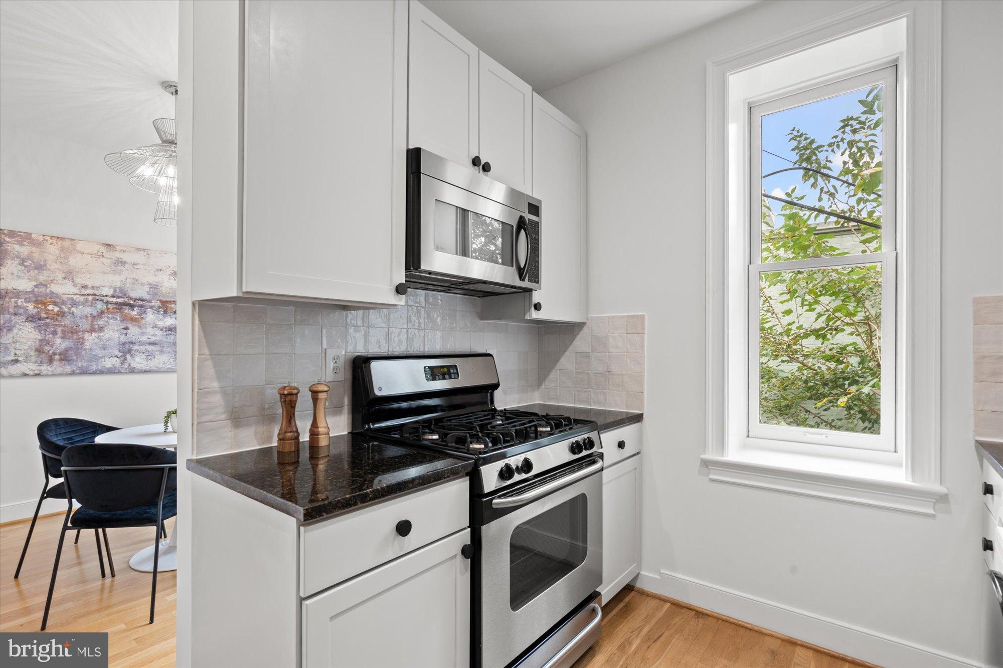 2145 N Street Northwest, Unit 3 Washington, DC 20037 - Photo 17 of 36 a kitchen with stainless steel appliances granite countertop a stove a microwave and a refrigerator