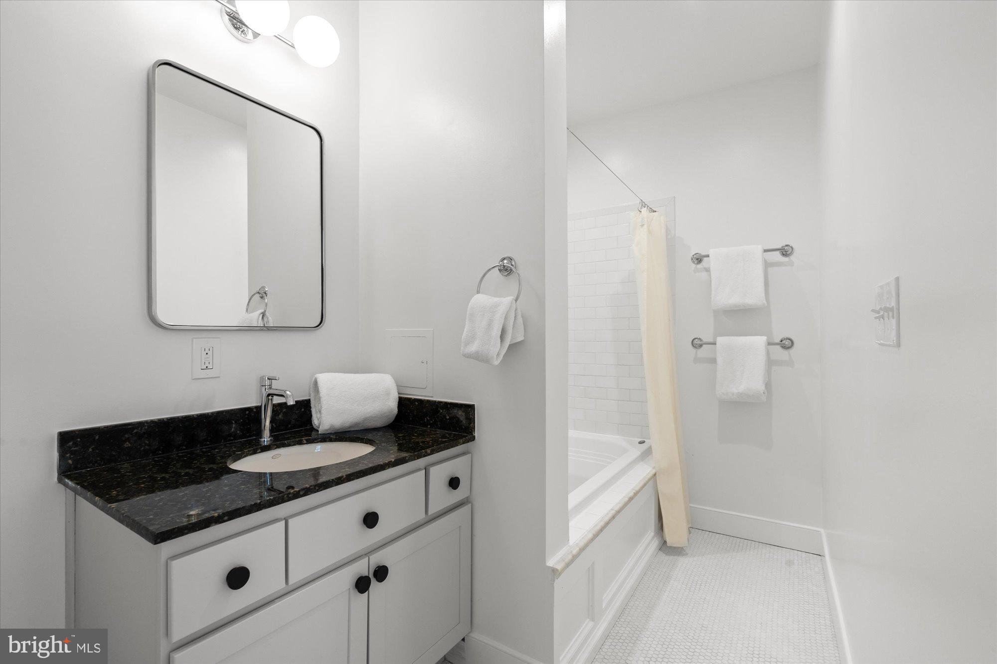 2145 N Street Northwest, Unit 3 Washington, DC 20037 - Photo 24 of 36 a bathroom with a granite countertop sink and a mirror