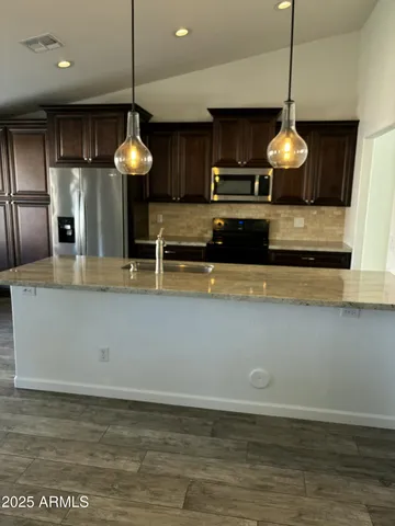a kitchen with kitchen island granite countertop a stove and a wooden floor