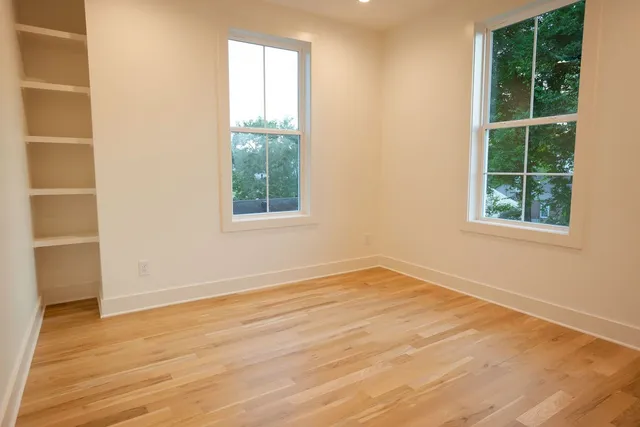 an empty room with wooden floor and windows