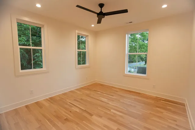 a view of an empty room with a window and wooden floor