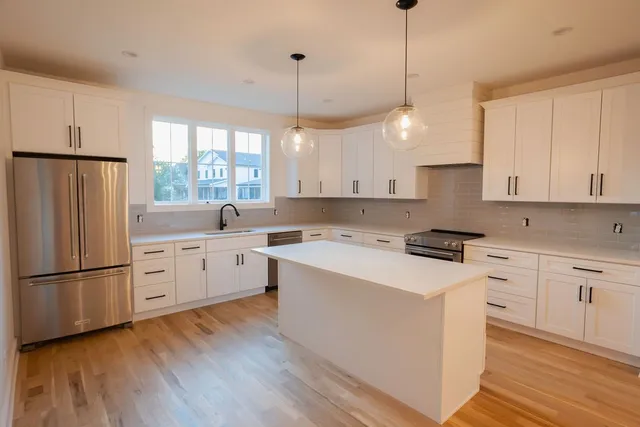 a kitchen that has a lot of white cabinets and wooden floor