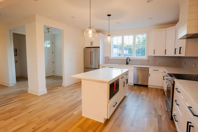 a kitchen that has a lot of white cabinets and wooden floor