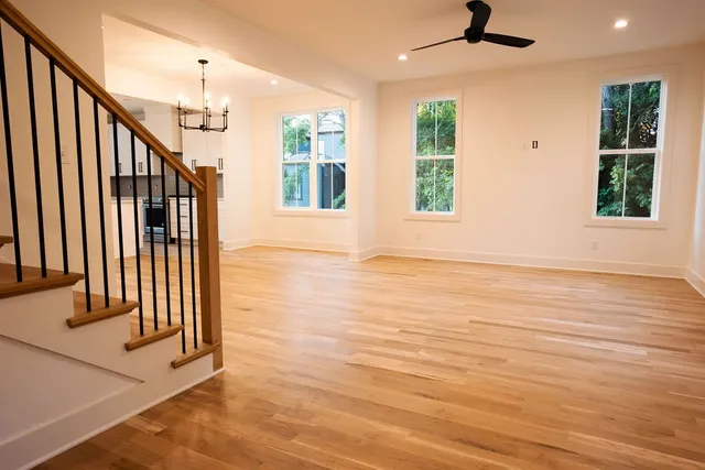an empty room with wooden floor fan and windows