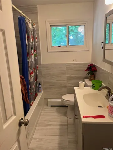 a bathroom with a sink a toilet a window and a shower