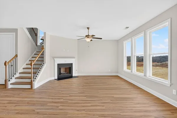 a view of an empty room with wooden floor fireplace and a window